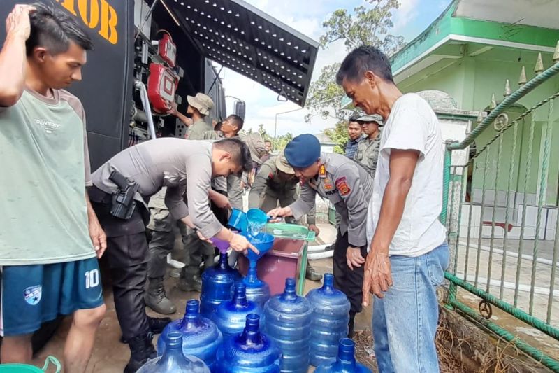 Personel Brimob Polda Jambi mengisi jerigen warga dengan air bersih di Desa Danau Lamo, Muaro Jambi, Rabu (14/8/2024). (ANTARA/HO-Polda Jambi)