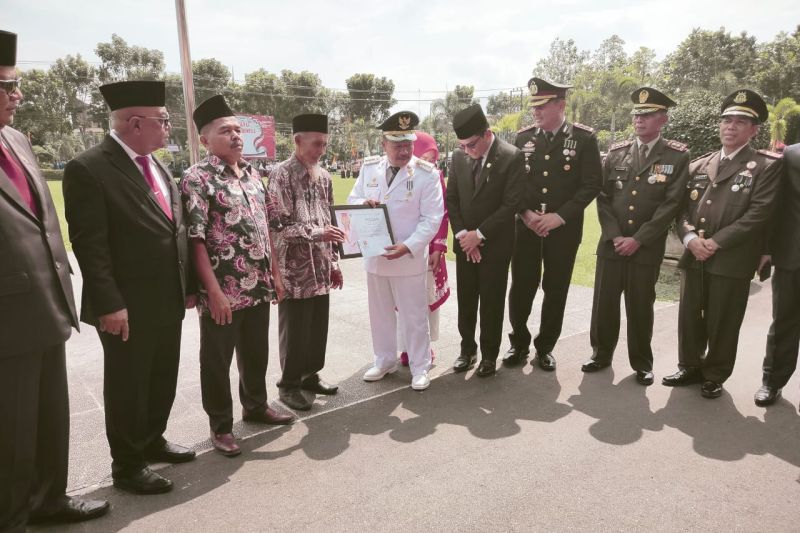 Bupati Agam Andri Warman menyerahkan piagam penghargaan kepada Tulih Sutan Kulipah (76) warga Limo Sariak, Nagari atau Desa Malalak Selatan, Kecamatan Malalak yang mengibarkan bendera di pohon setinggi 80 meter, Sabtu (17/8/2024). Antara/Yusrizal.