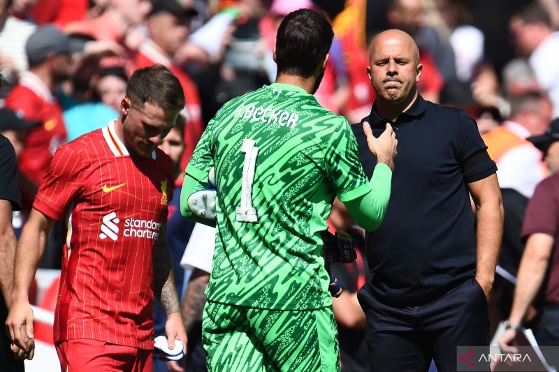 Manajer Liverpool asal Belanda Arne Slot berjabat tangan dengan kiper Liverpool asal Brazil #01 Alisson Becker setelah pertandingan sepak bola persahabatan pramusim antara Liverpool dan Sevilla di stadion Anfield di Liverpool, barat laut Inggris pada 11 Agustus 2024. (ANTARA/AFP/Peter Powell)