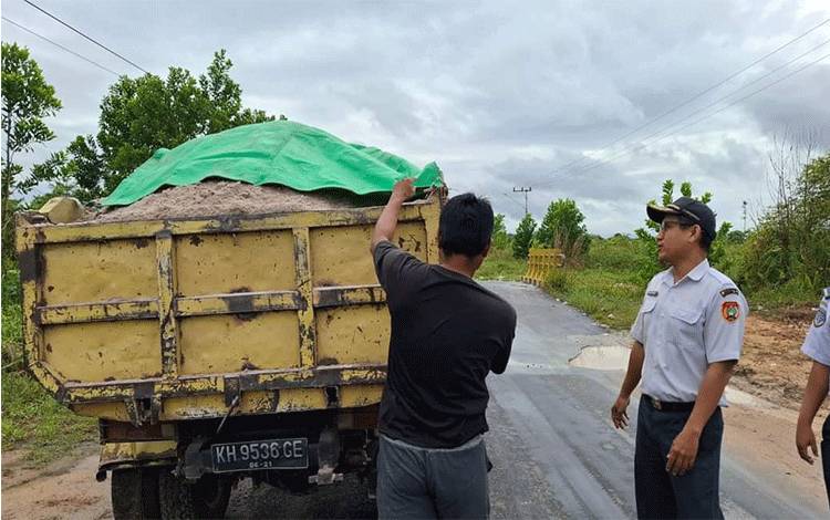 Personel Dishub Kobar saat menertibkan truk bermuatan pasir di ruas jalan Desa Kumpai Batu Atas.?