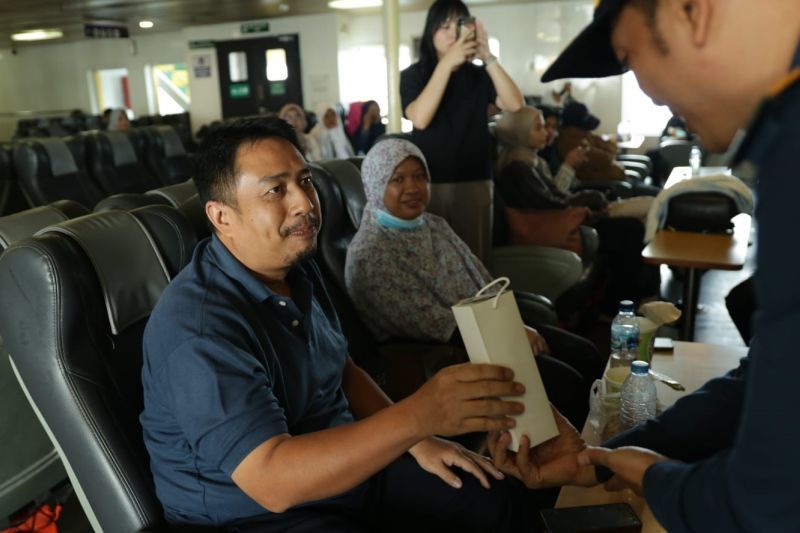 Seorang tim PT ASDP Indonesia Ferry (Persero) membagikan bingkisan kepada pelanggan di KMP Batumandi yang berlayar dari Merak menuju Bakauheni pada Minggu (1/9/2024). (Antara/HO/ASDP)