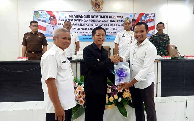 Pj Bupati Barito Utara, Muhlis menyerahkan buku petunjuk teknis kepada perwakilan salah satu Camat yaitu Camat Teweh Tengah, Jati Prayogo pada acara membangun komitmen bersama dalam rangka P4GN-PN tingkat Kabupaten Barito Utara, di aula Setda lantai I, Rabu 4 September 2024.(foto: Dhani)