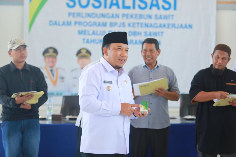 Wabup Siak Husni Merza saat menyerahkan Kartu Kepesertaan BPJS Ketenagakerjaan kepada Pekebun Sawit di Kecamatan Mempura. ANTARA/HO-Pemkab Siak