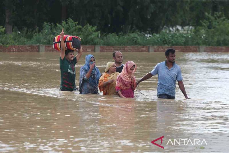 Ilustrasi dampak bencana iklim - Warga menyeberangi jalanan yang banjir di Cumilla, Bangladesh pada Jumat (23/8/2024). Banjir tersebut mengakibatkan 13 orang meninggal dunia, berdampak pada jutaan warga dan memaksa mereka mengungsi. ANTARA FOTO/Xinhua/rwa.