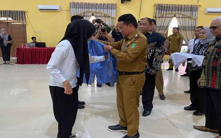 Pejabat Bupati Sukamara, Rendy Lesmana memasang jas almamater kepada mahasiswa yang mengikuti PKKMB di PSDKU Polnep Sukamara, Selasa, 10 September 2024. (FOTO: NORHASANAH)