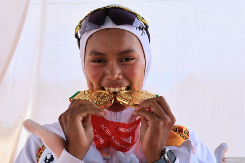 Atlet dayung asal Provinsi Jambi Mutiara Rahma Putri menggigit dua medali emas yang diraih pada cabang olahraga dayung Pekan Olahraga Nasional (PON) XXI Aceh-Sumatera Utara, Kamis (12/9/2024). ANTARA/Muhammad Zulfikar.