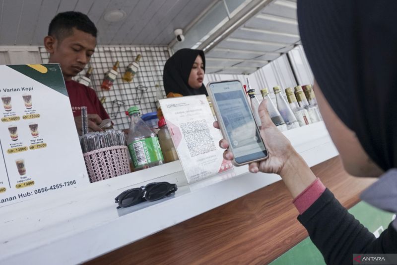 Konsumen membayar minuman yang dibelinya melalui ponsel dengan menggunakan fitur Quick Reponse Conde Indonesian Standard (QRIS) di kedai UMKM minuman, Kota Pekalongan, Jawa Tengah, Senin (9/9/2024). Gubernur Bank Indonesia (BI) Perry Warjiyo menyatakan kinerja transaksi ekonomi digital mencapai 1.845,27 juta transaksi atau tumbuh 30,50 persen secara tahunan dan transaksi uang elektronik tumbuh 22,61 persen secara tahunan dengan capaian 1.272,35 juta transaksi pada Juli 2024. ANTARA FOTO/Harviyan