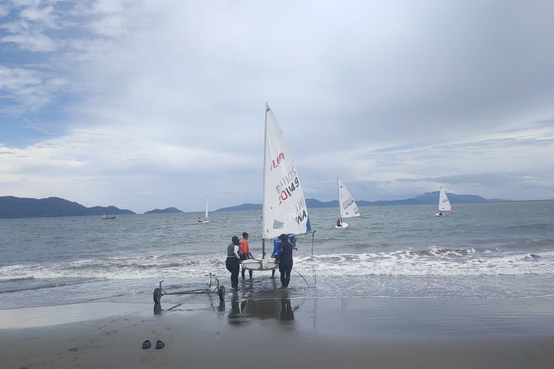 Para atlet layar di nomor ILCA 6 putri bersama ofisialnya masing-masing membawa layar menuju perlombaan dalam Pekan Olahraga Nasional (PON) XXI/2024 Aceh-Sumatera Utara di Pantai Kampung Jawa, Banda Aceh, Minggu (15/9/2024). ANTARA/Risky Syukur