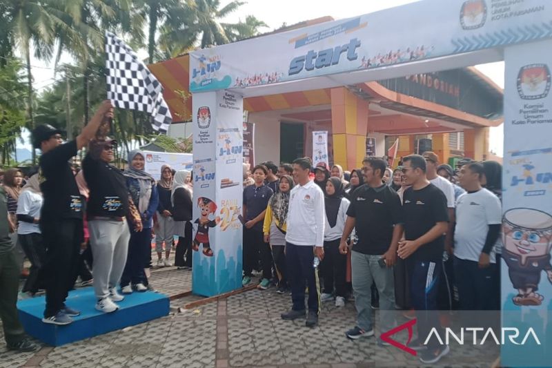 Komisioner KPU Sumbar Ory Sativa Syakban (kanan) bersama Ketua KPU Pariaman Ali Unan (kiri) mengangkat bendera pertanda dimulainya jalan santai yang dilaksanakan KPU setempat untuk meningkatkan partisipasi pemilih di daerah itu. ANTARA/istimewa