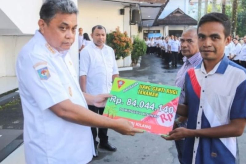 Penjabat Wali Kota Ambon, Dominggus N Kaya (kiri) menyerahkan ganti rugi tanaman jangka panjang milik warga Negeri Kilang, dan Hukurila, Kecamatan Leitimur Selatan, yang menjadi lokasi pembangunan jalan lingkar selatan Seri Hukurila, di Ambon, Rabu (25/9). ANTARA/ Ho- Diskominfo Ambon.