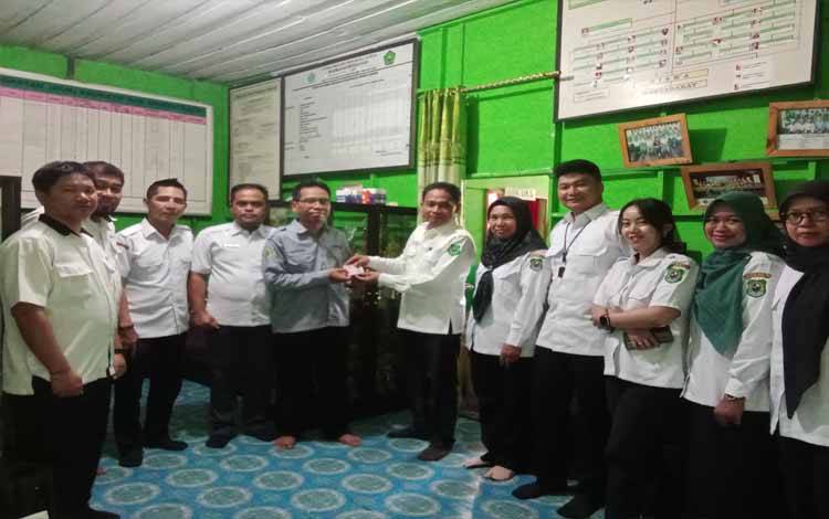 Plt Kabid Pendaftaran Penduduk, Solikin saat menyerahkan KIA kepada Kepala MI Manarul Huda, Rabu, 25 September 2024. (FOTO: IST)