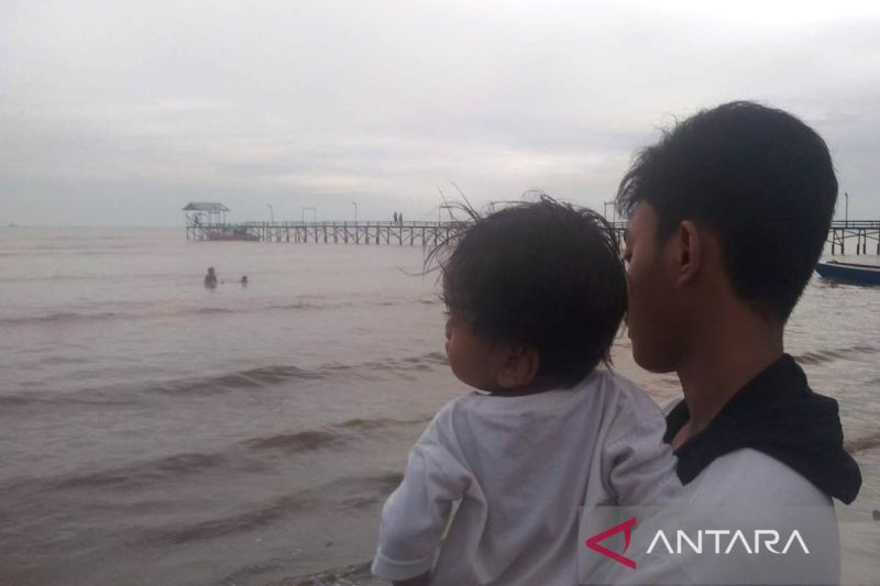 Ilustrasi: Seorang warga sedang menggendong anak kecil di Pantai Kersik Biru, Kecamatan Marangkayu, Kabupaten Kutai Kartanegara, Kaltim. (ANTARA/ M Ghofar)