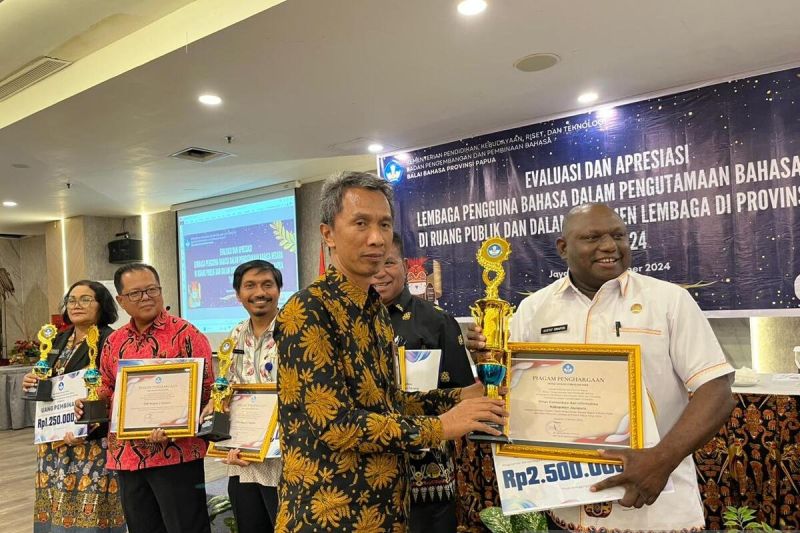 Kepala Balai Bahasa Papua Sukardi Gau saat menyerahkan piagam penghargaan terbaik kedua nominasi penggunaan bahasa Indonesia baik dan benar di ruang publik kepada Kepala Diskominfo Kabupaten Jayapura Gustaf Griapon. ANTARA/Yudhi Efendi