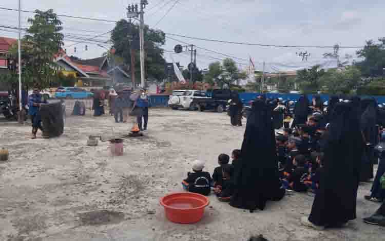 Petugas pemadam kebakaran saat mempraktikkan pemadaman api menggunakan kain atau handuk basah kepada anak-anak TK yang berkunjung, baru - baru ini (FOTO: IST)