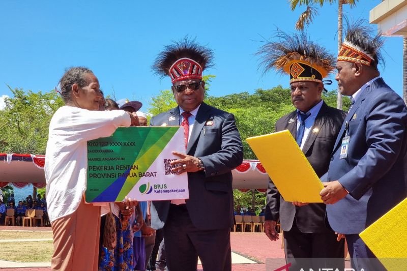 Penjabat Gubernur Papua Barat Ali Baham Temongmere (tengah) menyerahkan secara simbolis jaminan sosial kepada salah satu pekerja rentan asli Papua di Manokwari, Sabtu(12/10/2024). (ANTARA/Fransiskus Salu Weking)