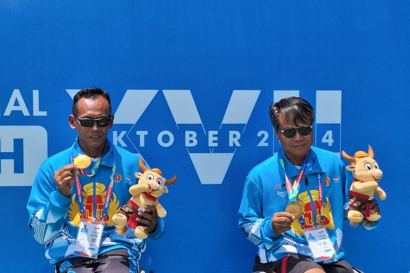 Atlet tenis kursi roda nomor ganda putra Yogyakarta, Sarjiyanto (kiri) bersama dengan Sukasno (kanan) menunjukkan medali emas Pekan Paralimpiade Nasional (Peparnas) XVII Solo 2024 di Lapangan Tenis Manahan, Solo, Jawa Tengah, Sabtu (12/10/2024). (ANTARA/FAJAR SATRIYO)