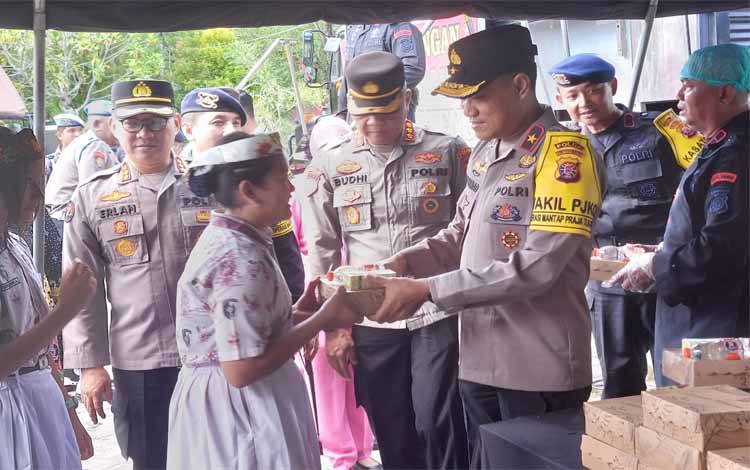 Wakapolda Kalteng Brigjen Rakhmad Setyadi saat menyerahkan makanan gratis kepada siswi SDN 11 Langkai (Foto : PATHUR)