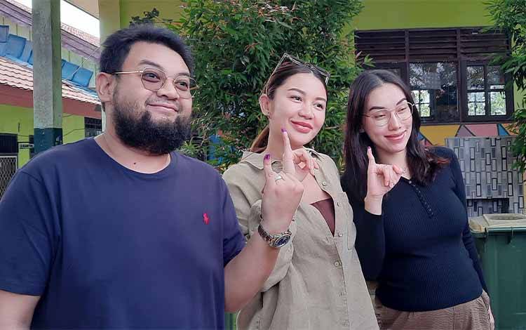 Monica Putri Rasyid dan Jemmy Adriyanor dan istri menunjukkan jari kelingking bertinta, usai mencoblos di TPS 14 Kelurahan Mendawai. (Foto : DANANG)