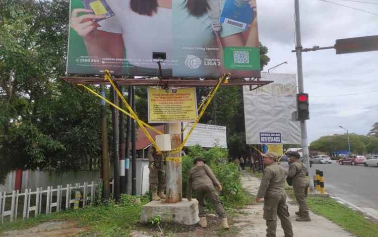 Anggota Satpol PP, DLH dan PTSP Kota Palangka Raya melakukan penyegelan sejumlah di baliho yang berada di kawasan Bundaran Kecil, Kamis (5/12/2024). ANTARA/Adi Wibowo