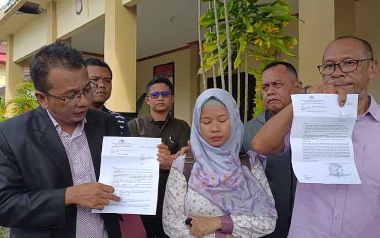 Yuliani tertunduk lesu didampingi kuasa hukumnya, Parlin B Hutabarat saat menunjukkan surat pemberitahuan kepada keluarga bahwa H ditahan. (FOTO: PATHUR)