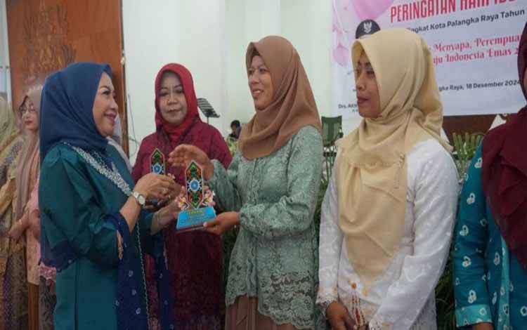 Penjabat Ketua TP PKK Kota Palangka Raya, Fifi Arfina menyerahkan plakat kepada PKK Kecamatan dan Kelurahan. (FOTO: HUMAS)