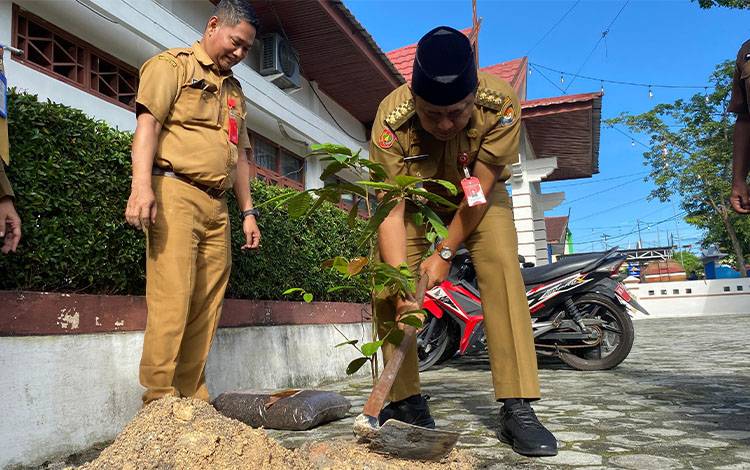 Pj Bupati Kobar Budi Santosa didampingi Kadis Perindagkopukm Kobar Alfan Khusnaini, saat melakukan penanaman pohon.