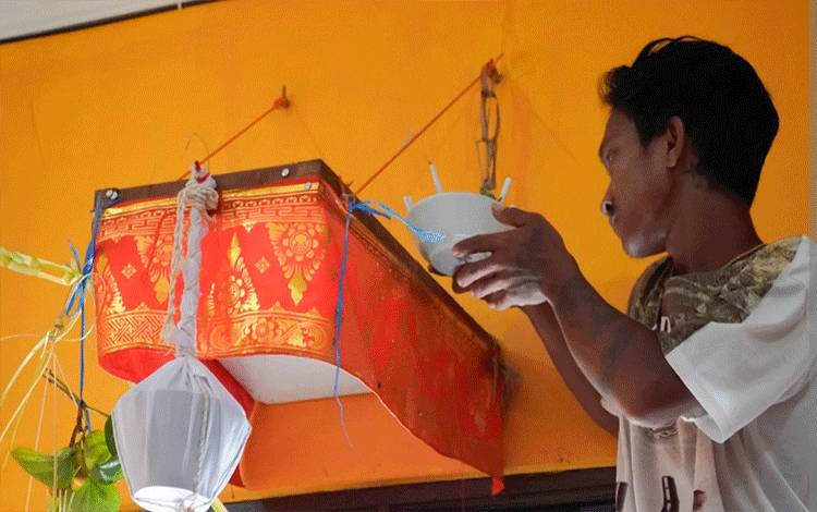 Pemangku Agama Hindu Kaharingan menaruh sesajen pada Balai Antang saat ritual Pakanan Sahur dan Mapas Lewu di Balai Basarah Tuyang Hasuling Riwut. (FOTO: PURBA)