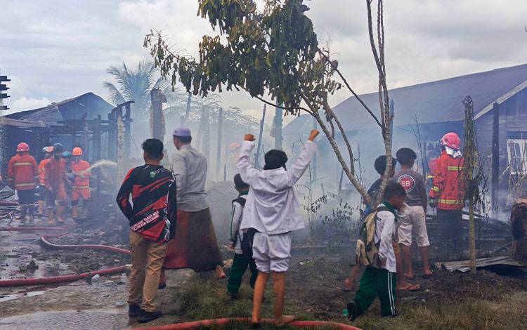 Petugas Pemadam saat melakukan pendinginan terhadap bangunan yang baru terbakar di Sampit, belum lama ini. (FOTO : DEVI)