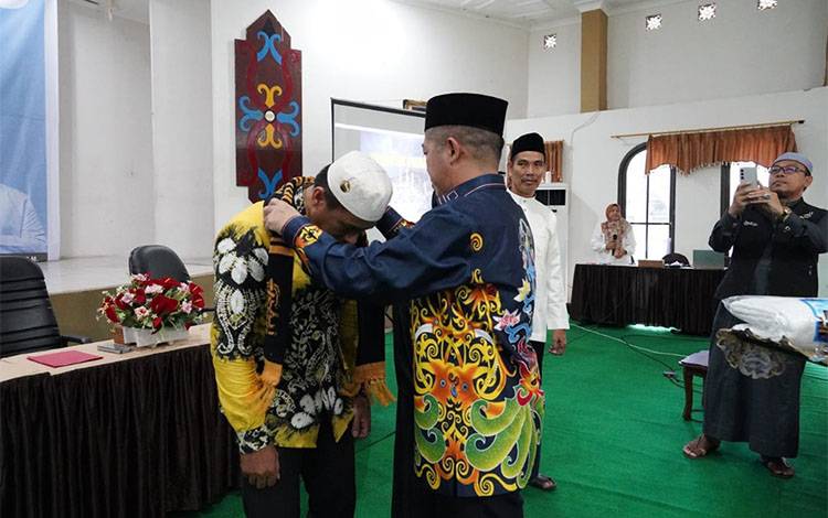 Plt Karo Kesra Ahmad Pahruka mengalungkan tanda kepesertaan umrah kepada salah satu jamaah. (FOTO: TOMY)