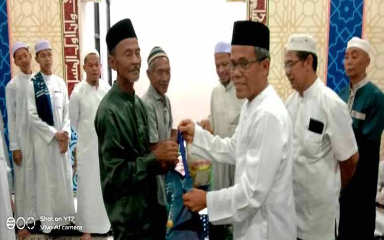 Kadis PUPR Barito Utara, M Iman Topik didampingi Sekdis PUPR, Rosmadian Noor dan Kabid Tata Kota, Zero menyerahkan bingkisan secara simbolis kepada pegawai Dinas PUPR usai buka puasa bersama di Musola Ar Raudhah, Kamis 6 Maret 2025.(foto: Dhani)