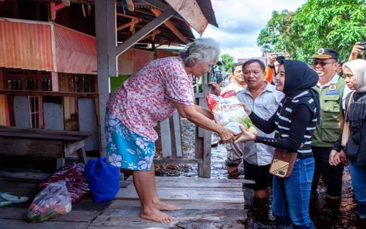 Ketua TP PKK Kalteng, Aisyah Thisia Agustiar Sabran menyerahkan bantuan beras kepada salah seorang warga terdampak banjir. (FOTO:AD)