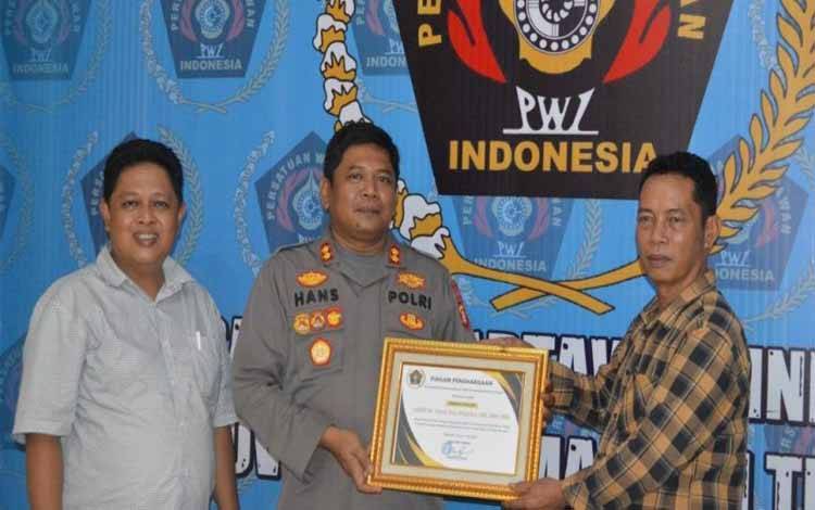 Ketua PWI Kalteng M Zainal didampingi Sekretaris PWI Kalteng Ika Lelunu saat menyerahkan penghargaan kepada Kapolres Seruyan AKBP Hans Itta Papahit di Balai PWI Kalteng