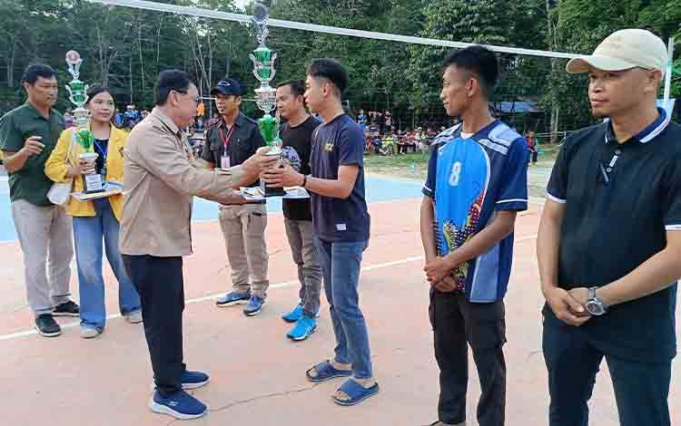 Asisten III Sekretariat Daerah Kabupaten Barito Timur, Edius Uhing, menyerahkan piala trofi piagam dan hadiah uang tunai kepada para pemenang, pada penutupan Turnamen Bola Voli HUT ke-66 Desa Tangkan, Jumat, 18 Juli 2025. (FOTO: AGUSTINUS BOLE MALO)