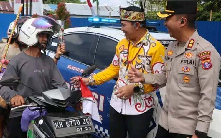Bupati dan Kapolres Pulpis membagikan bunga dan bendera kepada pengendara di Kahayan Hilir, Kamis, 14 Agustus 2025. (FOTO: RETHA)