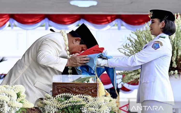 Presiden Prabowo Subianto (kiri) mencium duplikat Bendera Merah Putih saat diserahkan kepada Paskibraka pembawa baki Bianca Alessia Christabella untuk dikibarkan dalam Upacara Peringatan Detik-Detik Proklamasi Kemerdekaan ke-80 Republik Indonesia di Istana Merdeka, Jakarta, Minggu (17/8/2025). ANTARA/HO-BPMI Setpres/Cahyo. (Antara/HO)