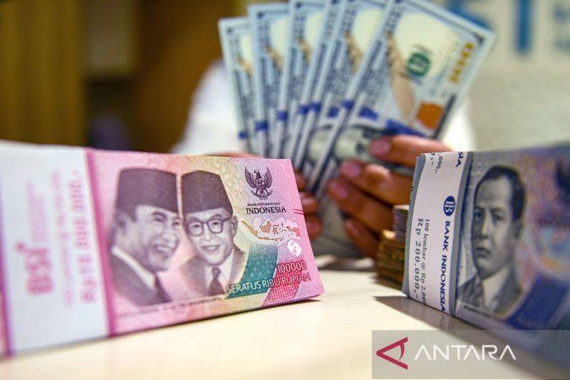 Petugas menunjukan uang pecahan dolar AS dan rupiah di Bank BSI, Jakarta. ANTARA FOTO/Muhammad Adimaja/Spt/pri.