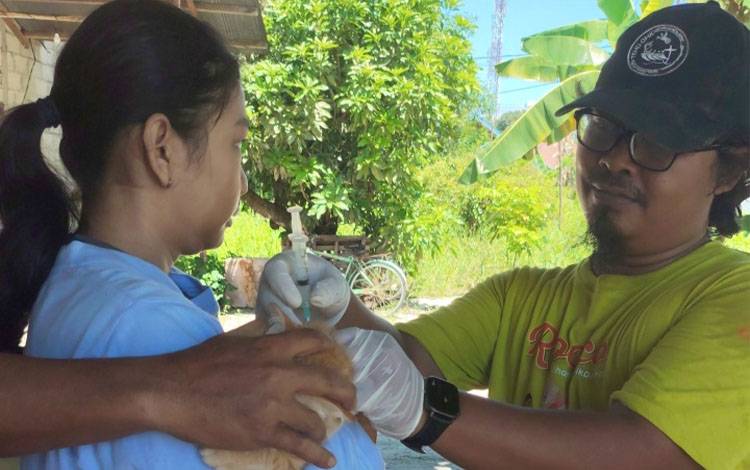 Vaksinator memberikan vaksin rabies kepada warga Panarung pada Sabtu, 1 November 2025. (FOTO: TESTI PRISCILLA)