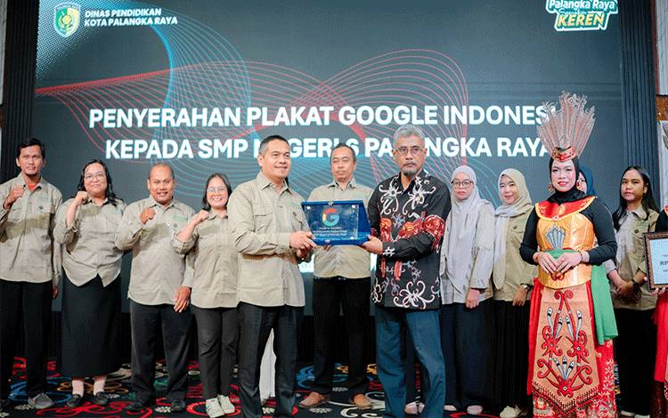 Kepala Dinas Pendidikan Palangka Raya Jayani (kanan) saat menyerahkan plakat dari google kepada Kepala SMPN 6 Palangka Raya Slamet Miharto. (Foto : IST)