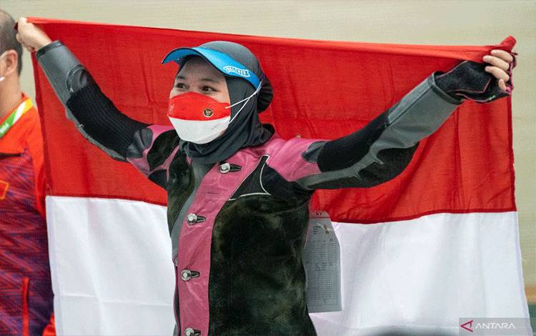 Petembak Dewi Laila Mubarokah membentangkan bendera Merah Putih setelah menjadi yang terbaik dalam nomor 10 meter air rifle putri menembak SEA Games 2021 Vietnam di Hanoi Sports Training and Competition Center, Hanoi, Vietnam, Senin (16/5/2022). Dewi meraih medali emas setelah menjadi yang terbaik dalam pengumpulan poin sebanyak 247. ANTARA FOTO/Sukmawati/APP/foc. (ANTARA FOTO/SUKMAWATI)