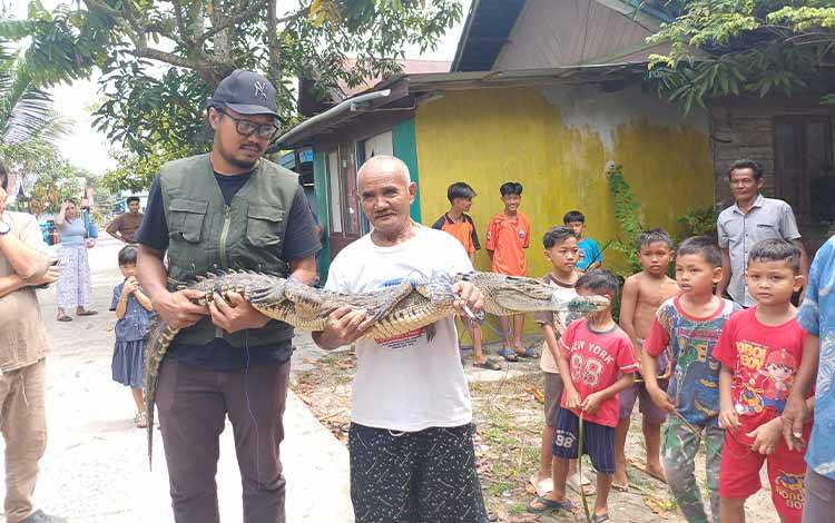 Buaya yang tertangkap jaring warga menjadi tontonan anak-anak, Jumat, 27 Maret 2026. (FOTO: DEWIP)