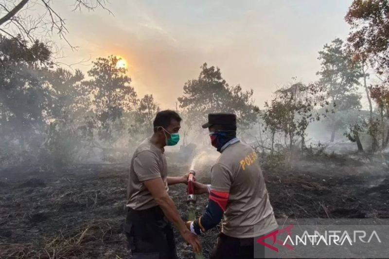 Dua anggota Polres Kubu Raya berjibakumemadamkan kebakaran lahan gambut di Kecamatan Sungai Raya (ANTARA/Rendra Oxtora)