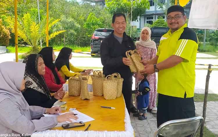 Ketua Pelaksana Kurban Masjid Al Farid, drh Ganjar Priyatno (kanan) menyerahkan hewan kurban yang dikemas dengan purun kepada masyarakat di lingkup kantor Pemko Palangka Raya pada Kamis, 28 Mei 2026.(FOTO: Istimewa)