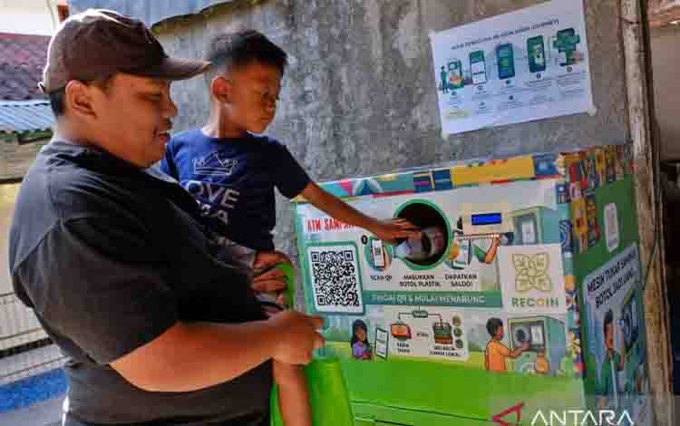 Seorang anak memasukkan botol plastik bekas minuman ke dalam ATM (anjungan tunai mandiri) Sampah di Dukuh, Magelang Tengah, Magelang, Jawa Tengah Selasa (30/6/2026). ATM Sampah karya Ben Swarna Sugi (36) merupakan inovasi berupa mesin penampung botol plastik bekas yang dilengkapi perangkat elektronik untuk menghitung jumlah sampah dan mengonversinya menjadi saldo uang digital, sebagai upaya meningkatkan kesadaran masyarakat akan pentingnya menjaga lingkungan sekaligus memberikan nilai ekonomi da
