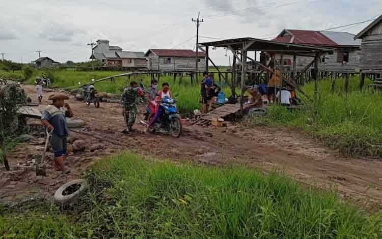 Babinsa Koramil 1016-01 Pahandut Bersama Warga Perbaiki Jalan Berlubang