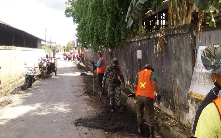 Babinsa Kelurahan Pahandut Bersihkan Drainase Bersama Warga