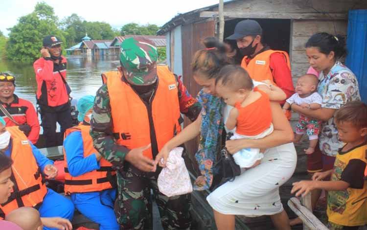 Babinsa Bersama Nakes dan MPA Evakuasi Ibu dan Balita Terdampak Banjir di Petuk Katimpun