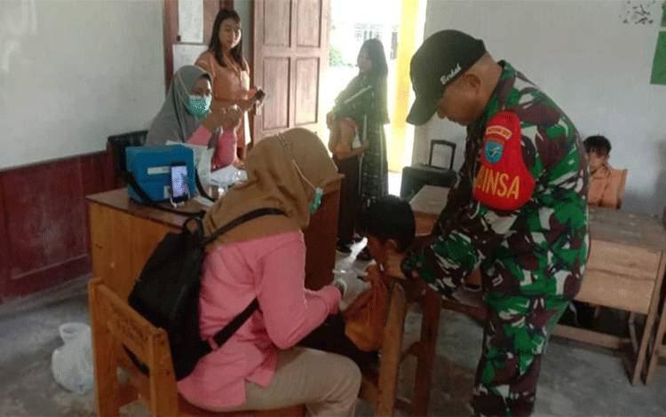 Babinsa Kapuas Hilir Dampingi Petugas Puskesmas Sukseskan Imunisasi Anak Sekolah
