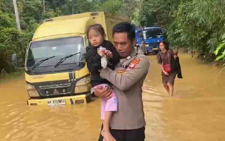 Polisi Gendong Bocah Bantu Seberangi Jalan yang Terendam Banjir